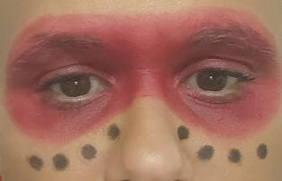 Tanamá Kao Tanamá Kao wearing red mask makeup with eight dots beneath.